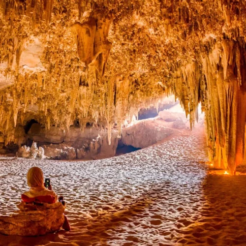 traveler admiring ancient limestone stalactites and desert rock formations inside djara cave in egypt