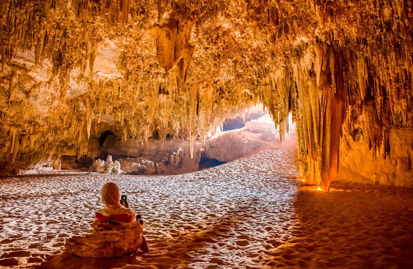 traveler admiring ancient limestone stalactites and desert rock formations inside djara cave in egypt