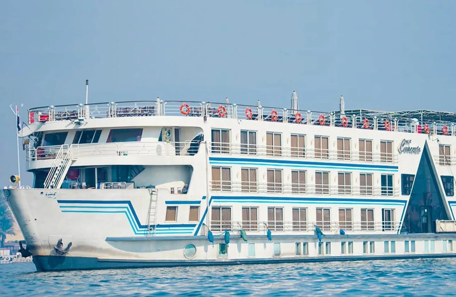 modern five star nile cruise ship moored along the scenic nile river bank in aswan under clear sky