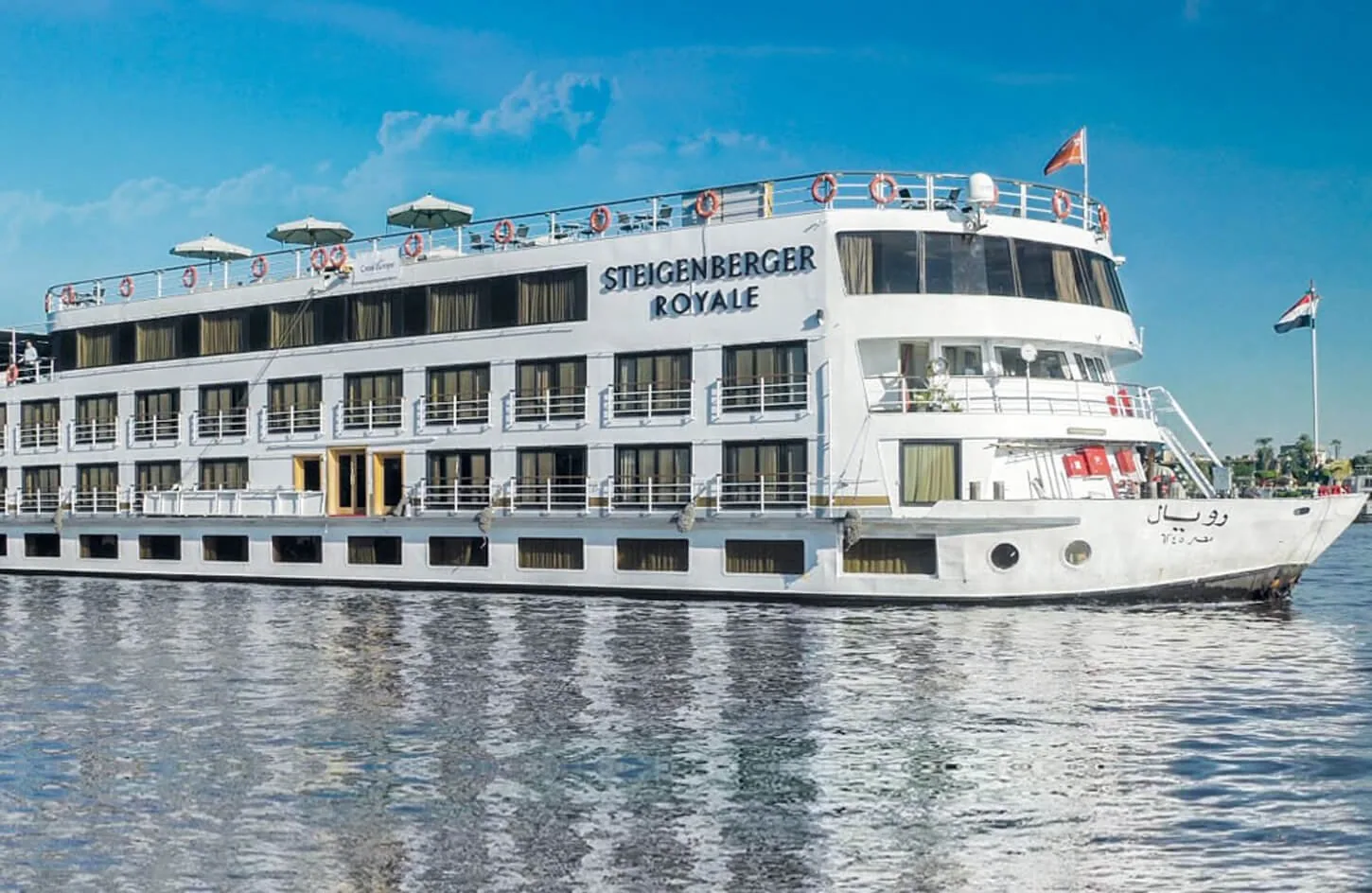 luxury white nile cruise ship sailing along calm nile waters surrounded by green palm trees and blue sky