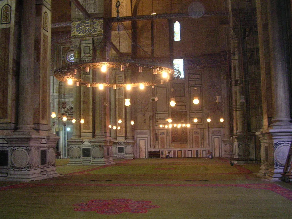 Prayer hall of Al-Rifa'i Mosque with stone pillars and a circular chandelier