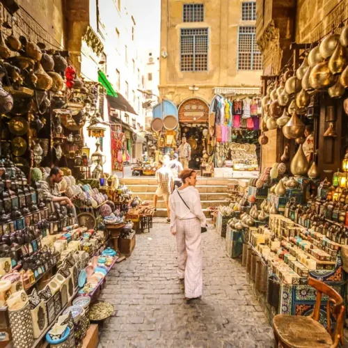 Traveler walking a lantern-lined alley in the Khan El Khalili bazaar