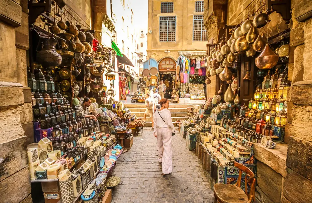 Traveler walking a lantern-lined alley in the Khan El Khalili bazaar