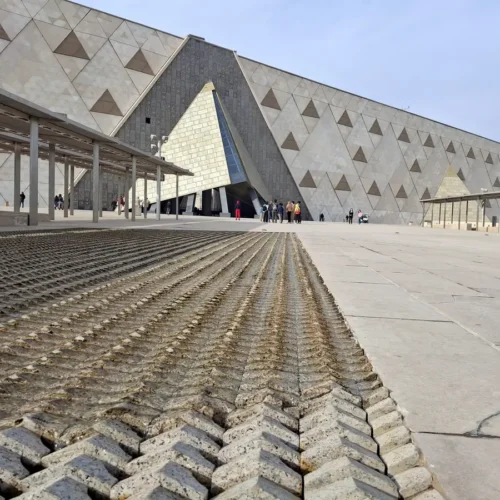 The angular stone facade of the Grand Egyptian Museum under a clear sky