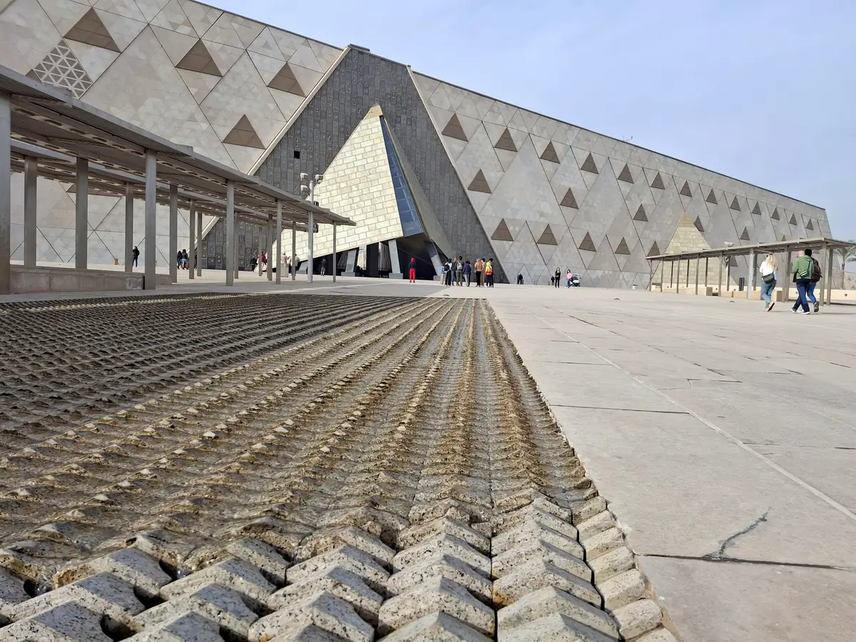 The angular stone facade of the Grand Egyptian Museum under a clear sky