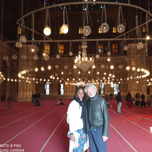 Couple standing under chandeliers inside the Muhammad Ali Mosque at the Citadel