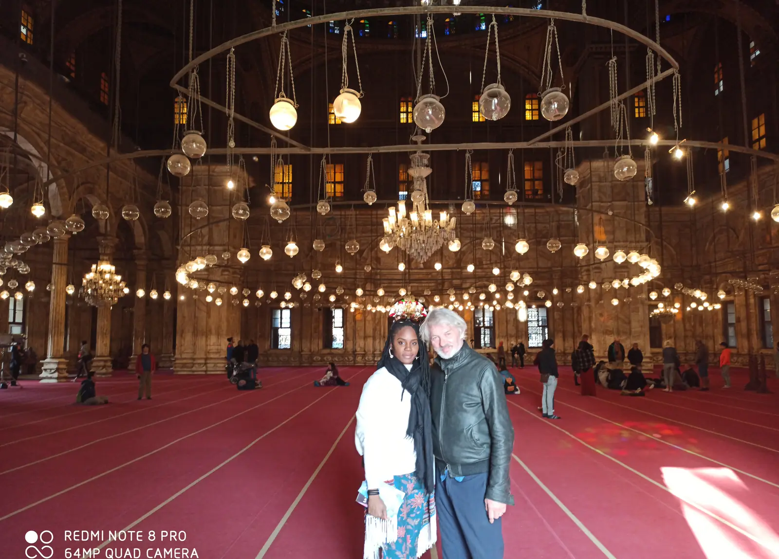 Couple standing under chandeliers inside the Muhammad Ali Mosque at the Citadel