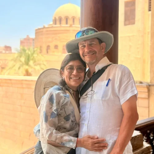 Couple posing on a wooden balcony with a historic dome behind in Old Cairo