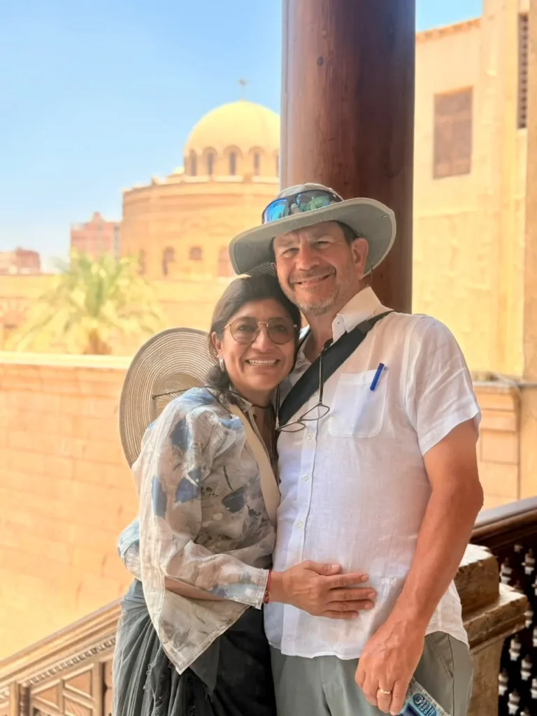 Couple posing on a wooden balcony with a historic dome behind in Old Cairo