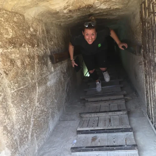 Woman climbing the wooden staircase inside a Dahshur pyramid's descending passage