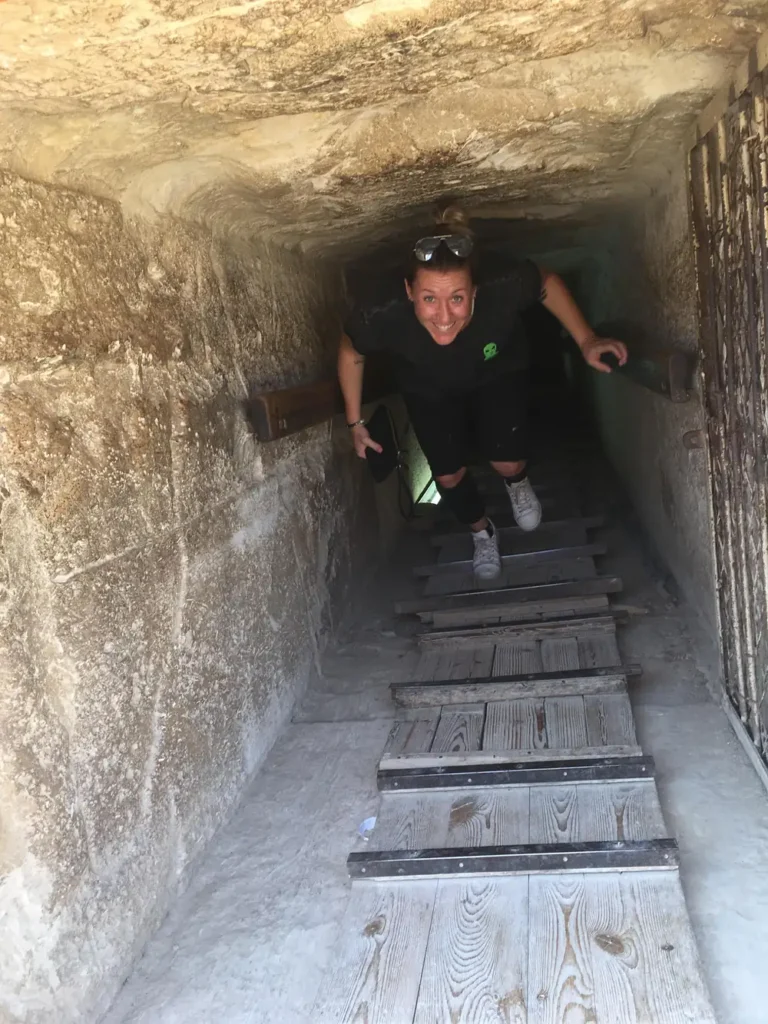 Woman climbing the wooden staircase inside a Dahshur pyramid's descending passage