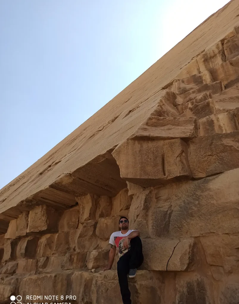 Man leaning against the massive limestone blocks of the Red Pyramid at Dahshur