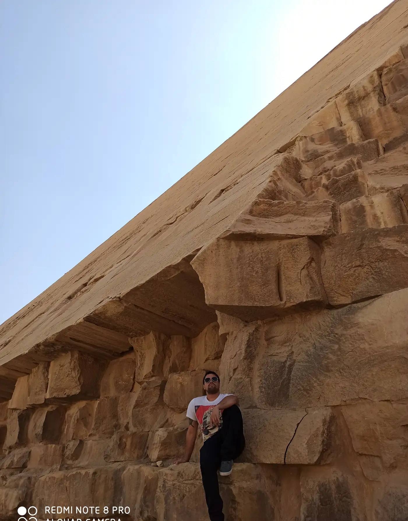 Man leaning against the massive limestone blocks of the Red Pyramid at Dahshur