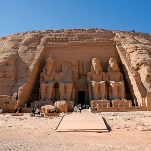 four colossal seated statues of pharaoh ramesses ii carved into the sandstone cliff facade at abu simbel temple