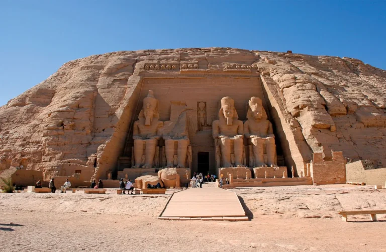 four colossal seated statues of pharaoh ramesses ii carved into the sandstone cliff facade at abu simbel temple