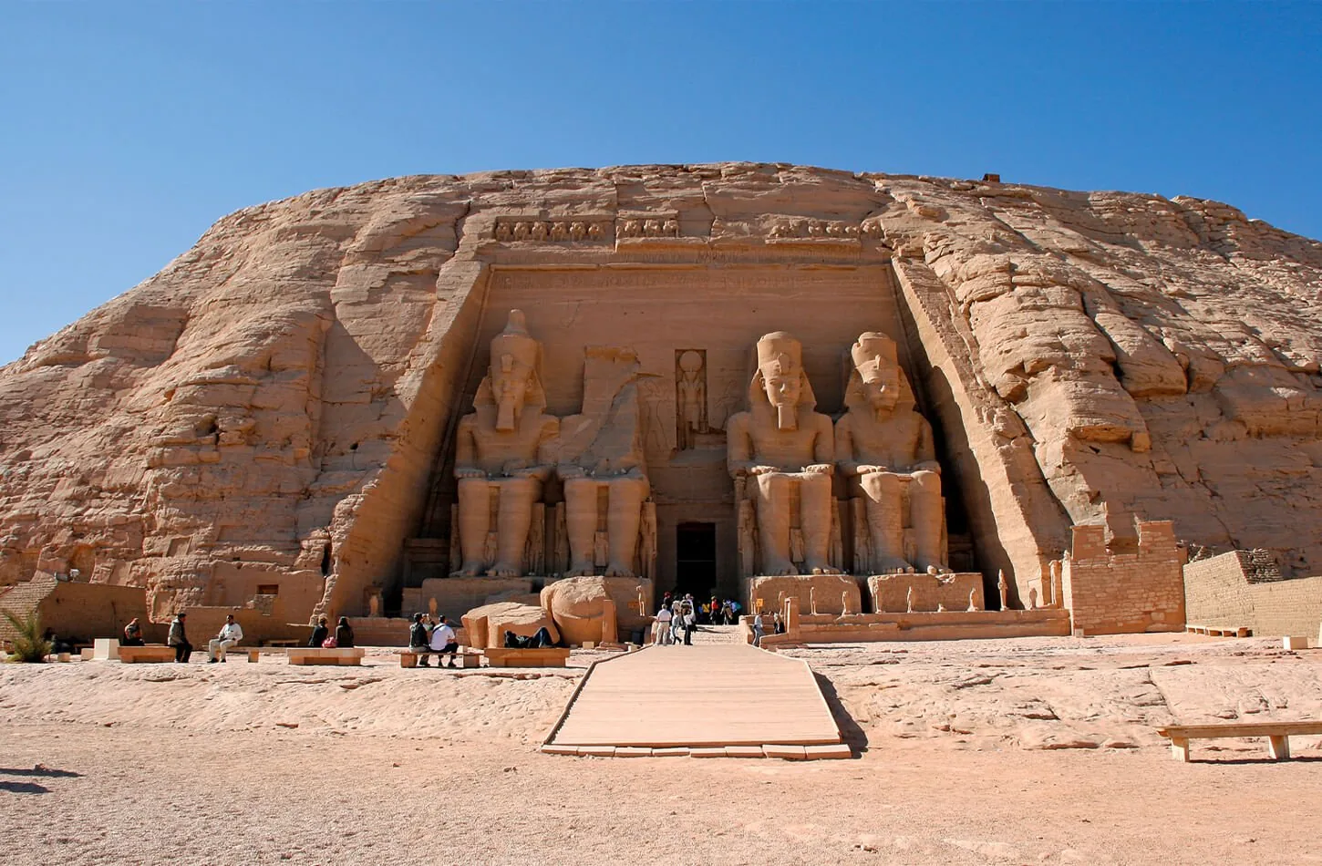 four colossal seated statues of pharaoh ramesses ii carved into the sandstone cliff facade at abu simbel temple