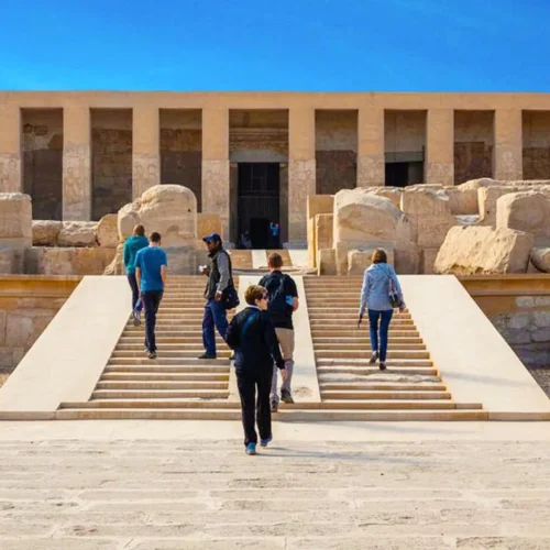travelers approaching the grand limestone entrance of abydos temple on a cultural excursion from luxor