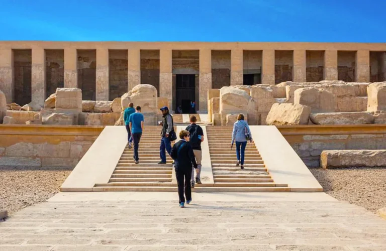 travelers approaching the grand limestone entrance of abydos temple on a cultural excursion from luxor