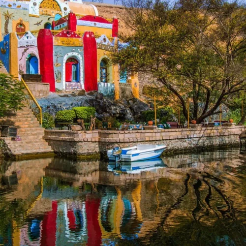 vibrantly painted blue and yellow houses along the rocky nile river bank at a traditional nubian village in aswan