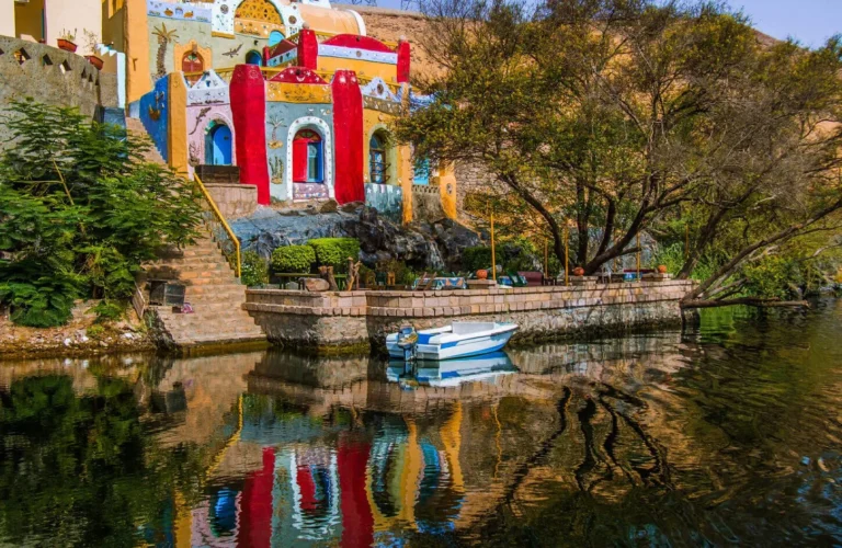 vibrantly painted blue and yellow houses along the rocky nile river bank at a traditional nubian village in aswan