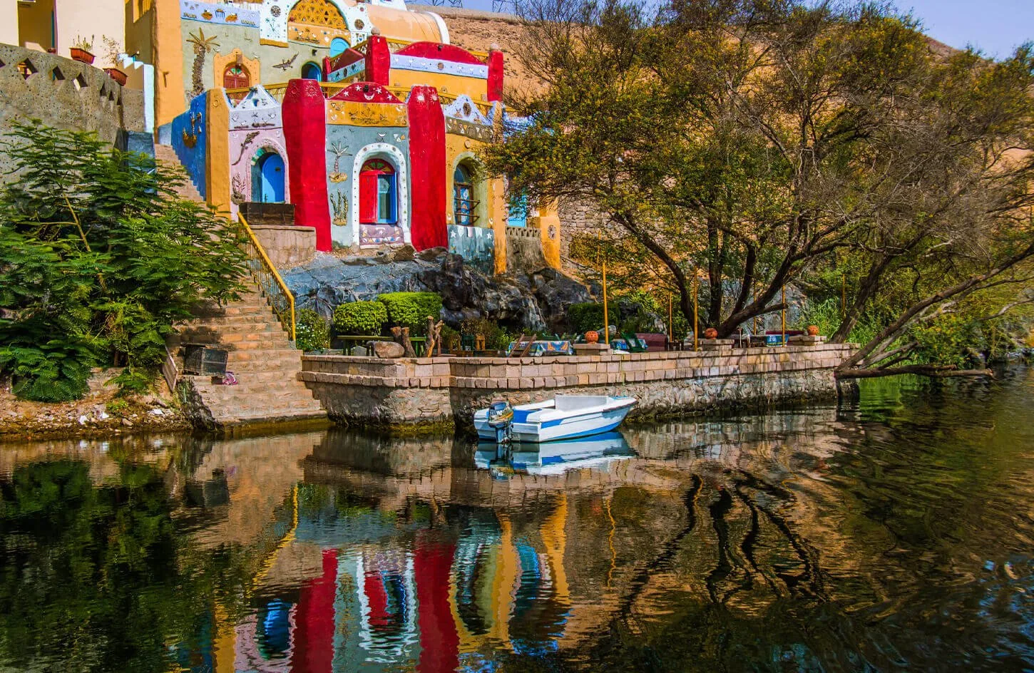 vibrantly painted blue and yellow houses along the rocky nile river bank at a traditional nubian village in aswan