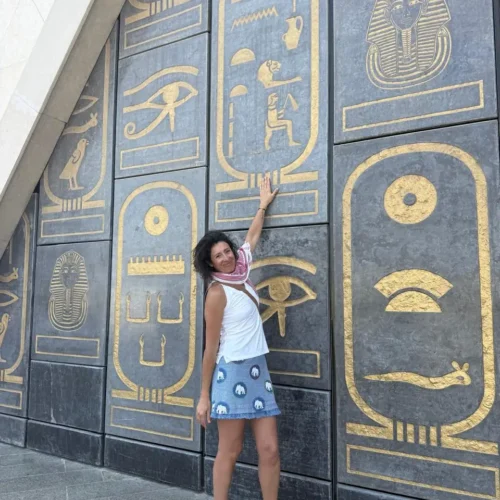 Traveler touching the gold hieroglyph and cartouche wall at the museum entrance