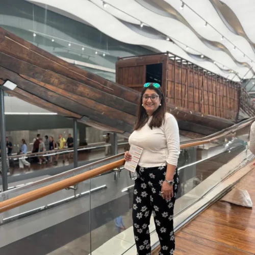 Traveler beside the ancient wooden Khufu Solar Boat at the Grand Egyptian Museum