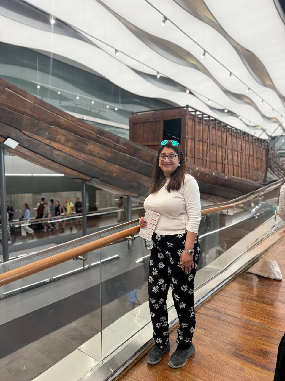 Traveler beside the ancient wooden Khufu Solar Boat at the Grand Egyptian Museum