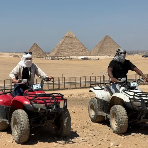 Two ATV riders facing each other with the three Giza pyramids behind