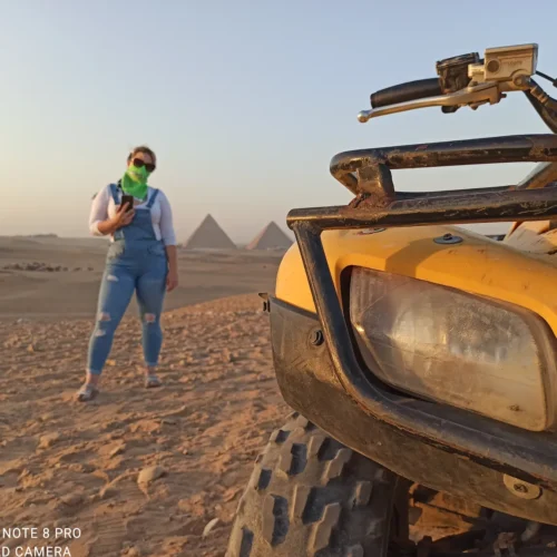 Traveler beside a yellow ATV with the Giza pyramids at golden hour