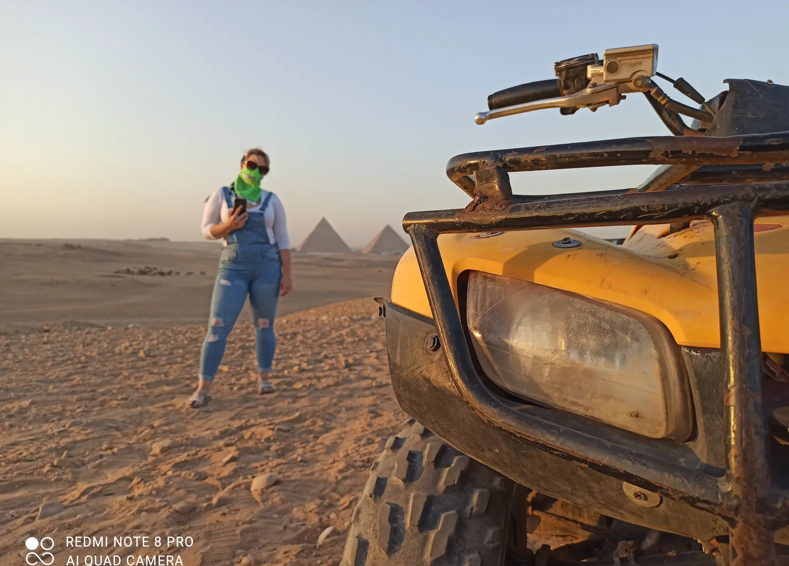 Traveler beside a yellow ATV with the Giza pyramids at golden hour