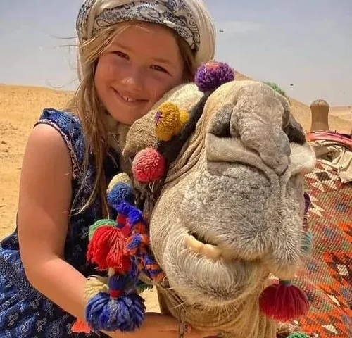 Traveler hugging a camel on the Giza desert plateau