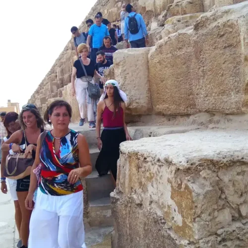 Group of travelers walking down the stone blocks of a Giza pyramid