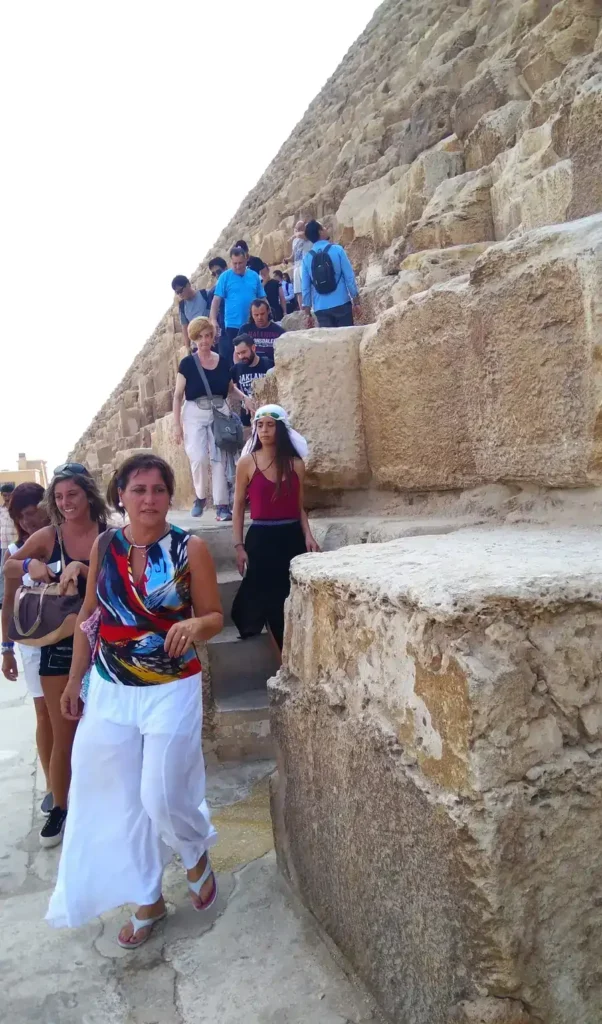 Group of travelers walking down the stone blocks of a Giza pyramid
