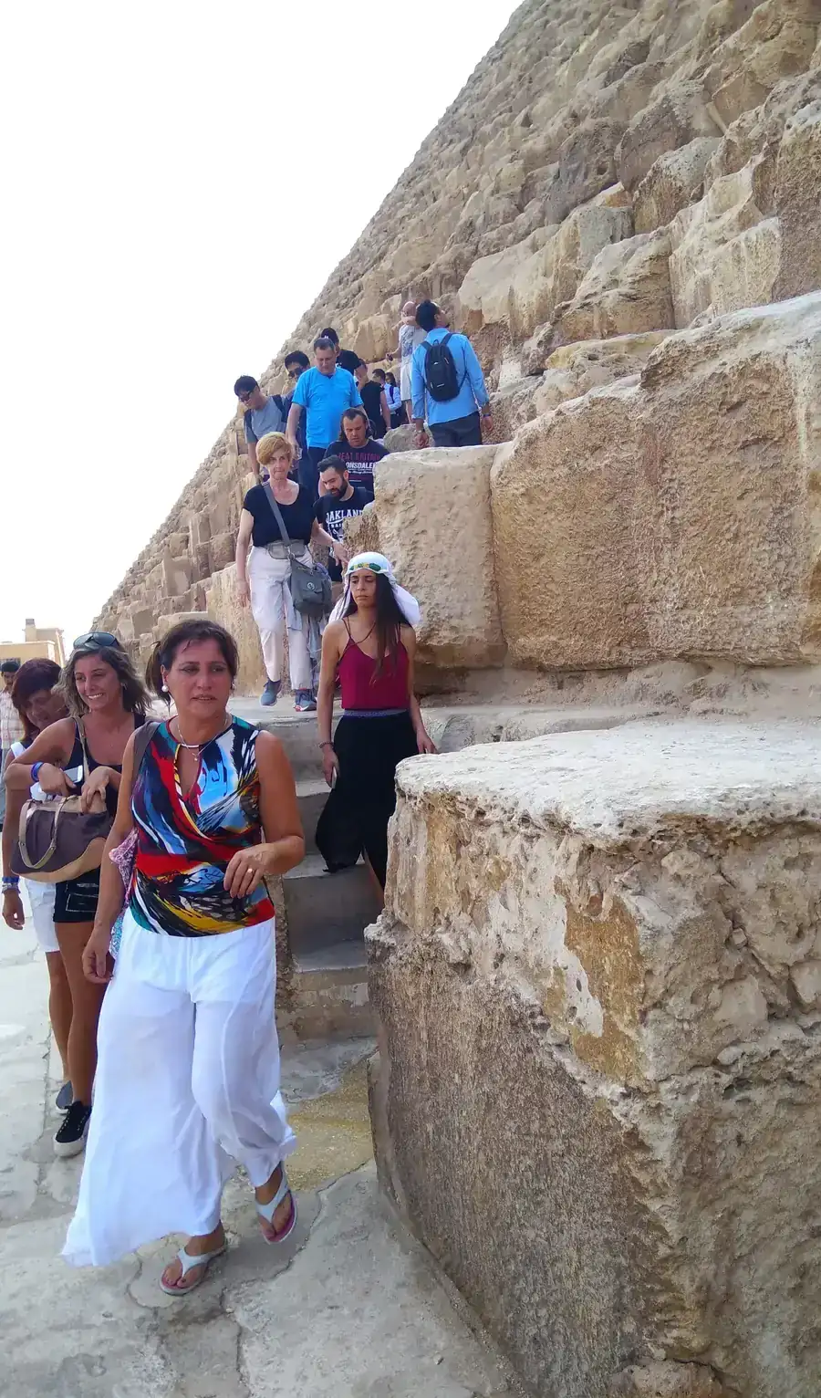Group of travelers walking down the stone blocks of a Giza pyramid