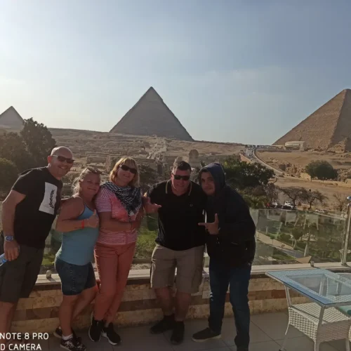 Group of five travelers on a terrace overlooking the three Giza pyramids