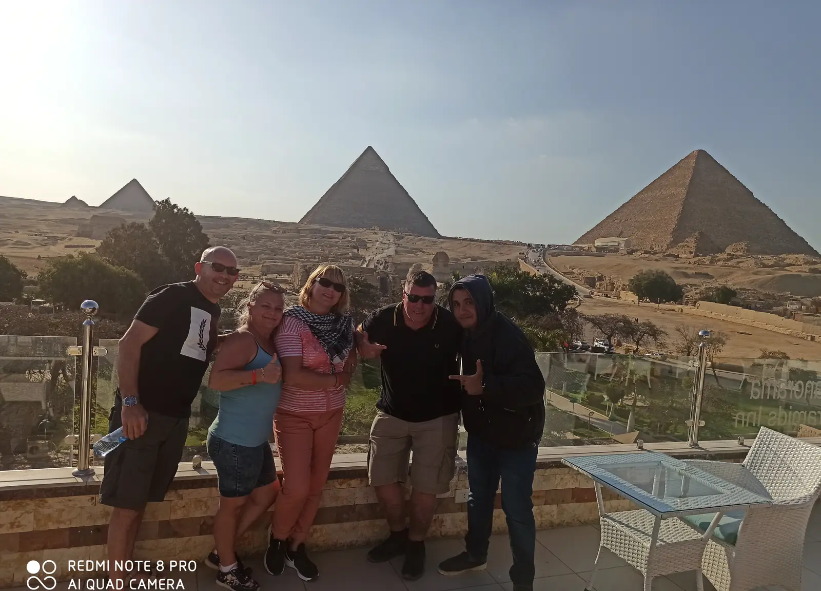 Group of five travelers on a terrace overlooking the three Giza pyramids