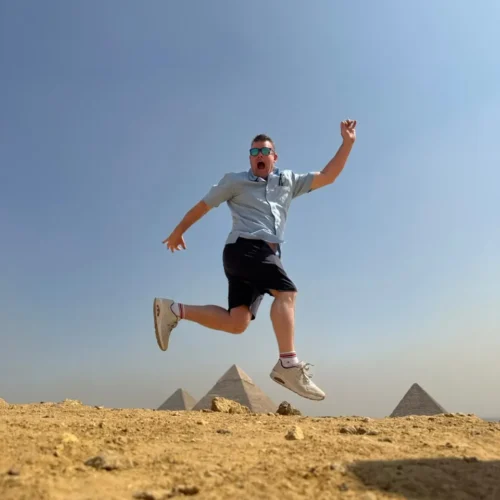 Traveler jumping mid-air with the Giza pyramids on the horizon