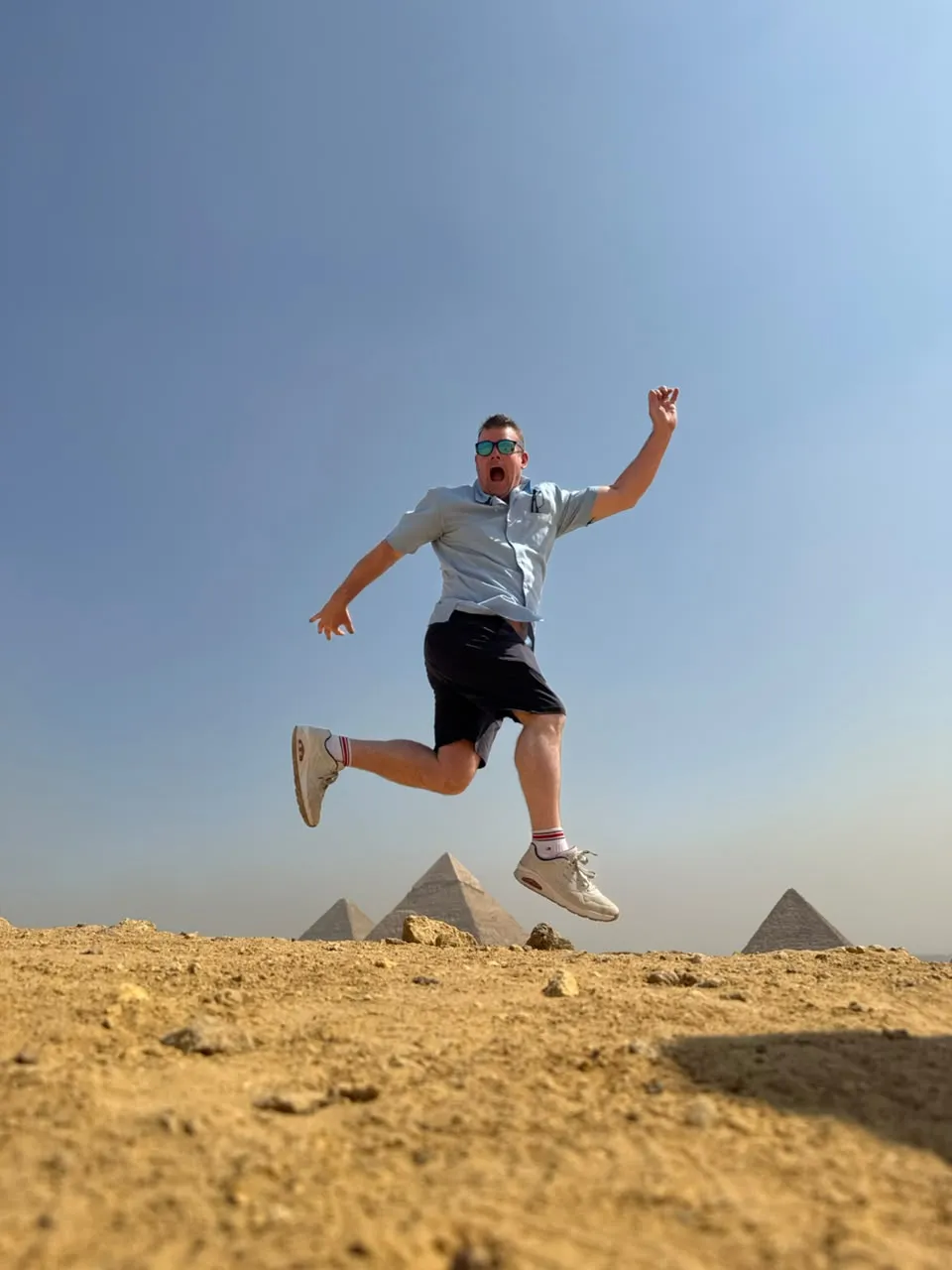 Traveler jumping mid-air with the Giza pyramids on the horizon
