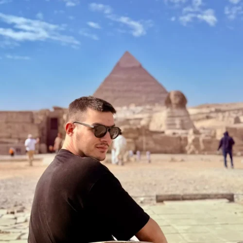 Traveler seated looking back toward the Great Pyramid and Sphinx at Giza