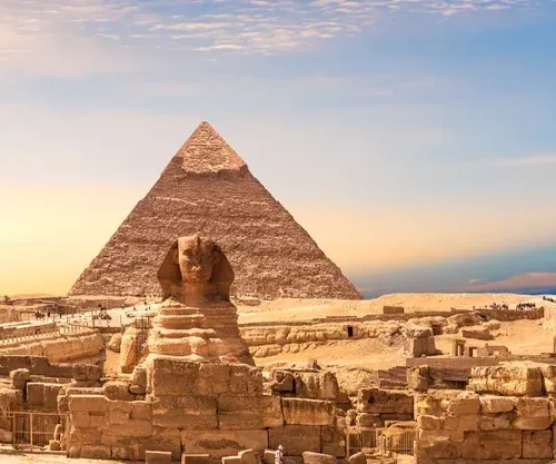 Panorama of the three Giza pyramids and the Great Sphinx under a golden sky