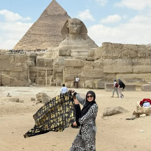 Woman holding a pharaonic shawl before the Great Sphinx and the Khafre pyramid at Giza