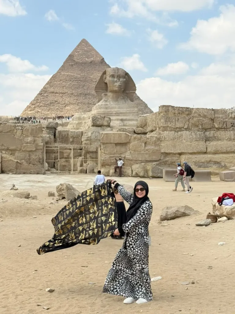 Woman holding a pharaonic shawl before the Great Sphinx and the Khafre pyramid at Giza