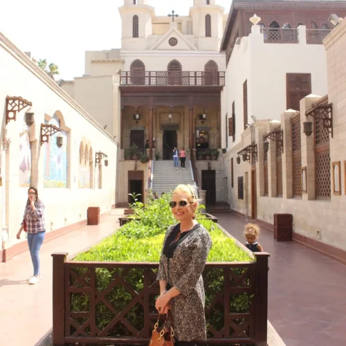 Traveler smiling in the Hanging Church courtyard with bell towers behind