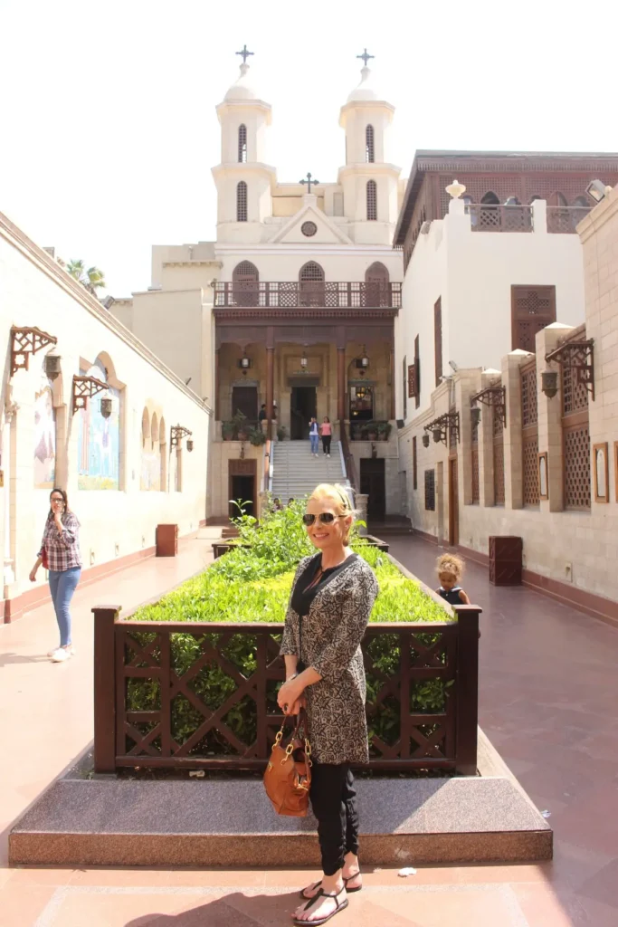 Traveler smiling in the Hanging Church courtyard with bell towers behind