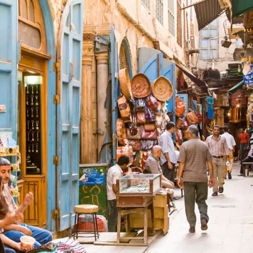 Narrow bazaar alley with light-blue wooden doors and hanging crafts in Khan El Khalili
