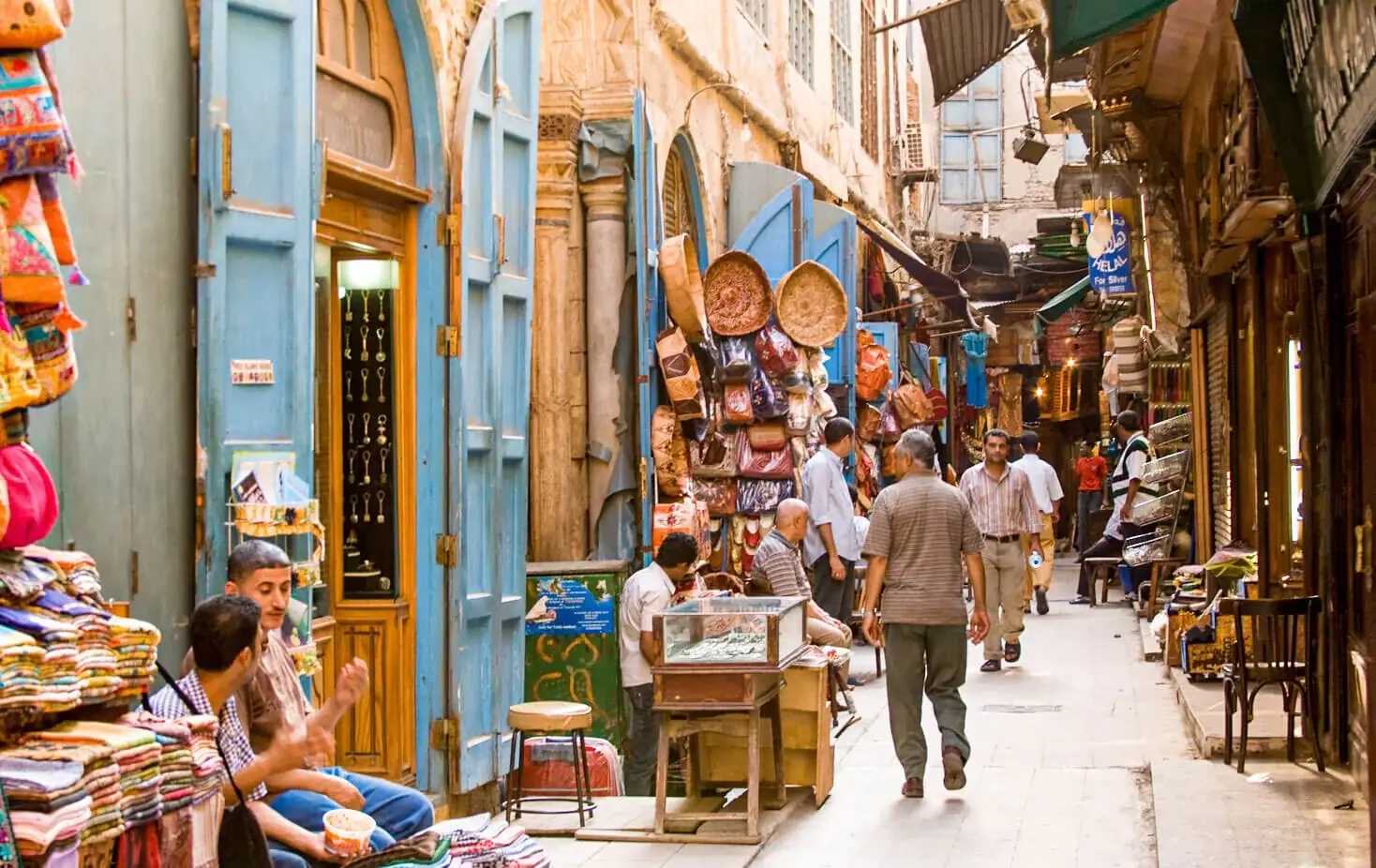 Narrow bazaar alley with light-blue wooden doors and hanging crafts in Khan El Khalili