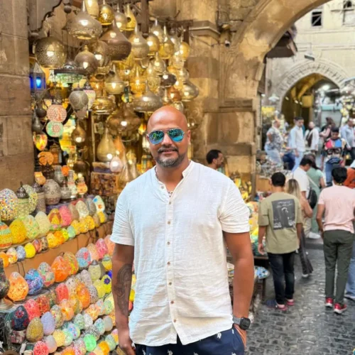 Traveler smiling beside glowing mosaic lanterns in a Khan El Khalili shop