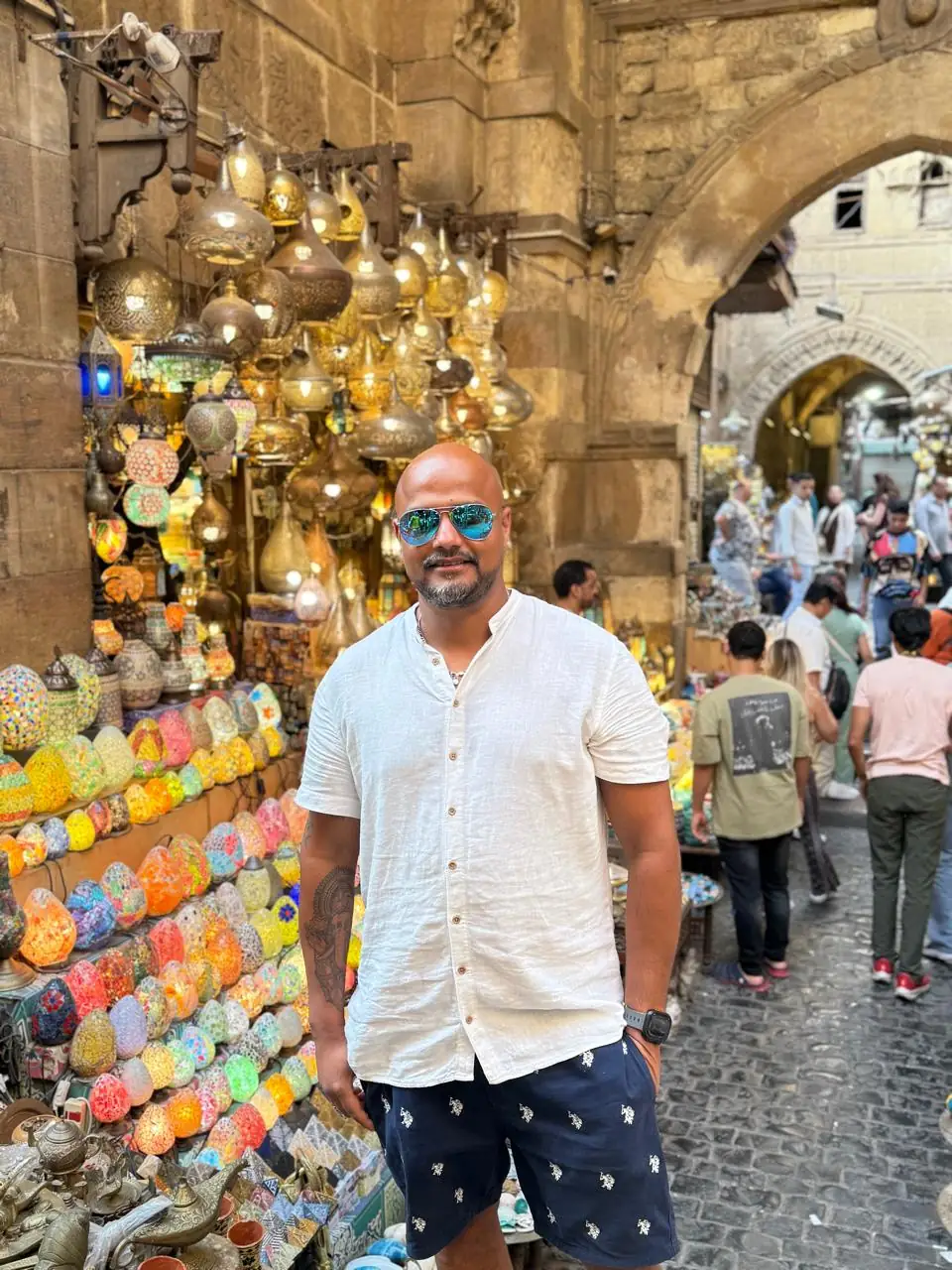 Traveler smiling beside glowing mosaic lanterns in a Khan El Khalili shop