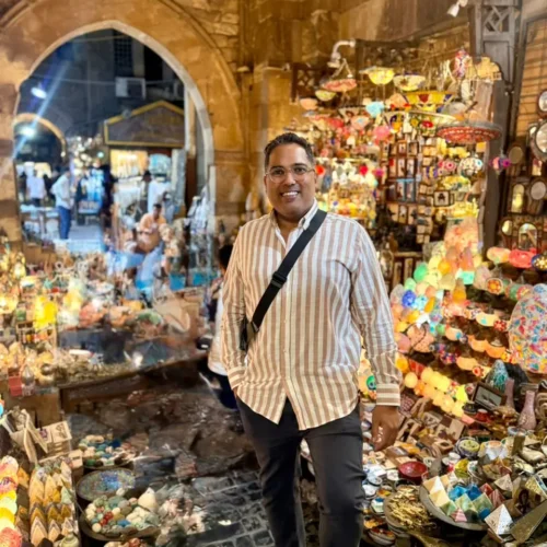 Traveler on stone steps before a wall of colorful lanterns in Khan El Khalili